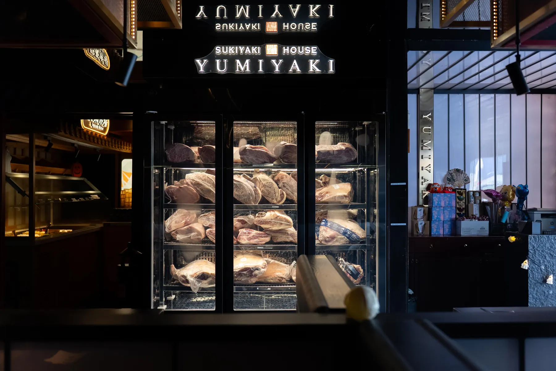 Whole cuts of wagyu in the cabinet beneath the Yumiyaki sign
